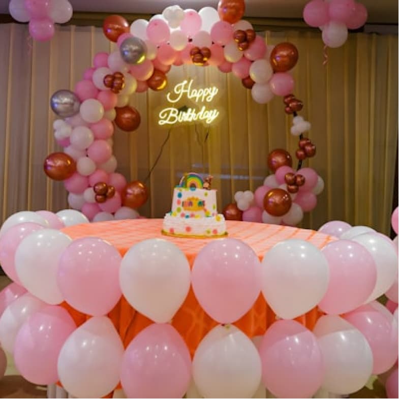 Birthday celebration with pink and gold balloon arch