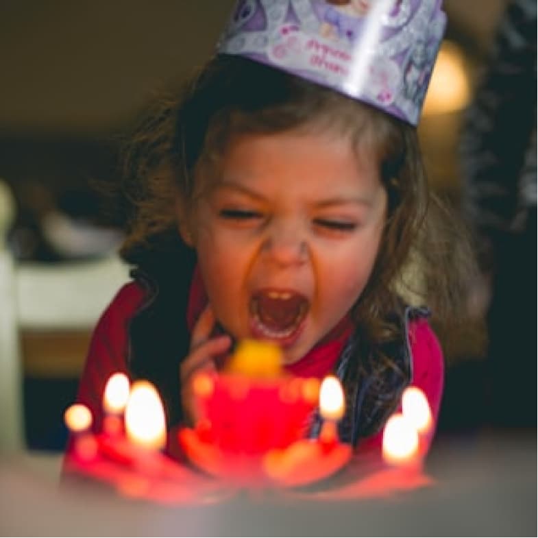 Toddler blowing birthday cake candles