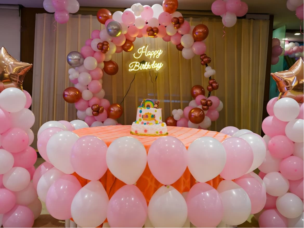 Festive birthday party celebration with balloon backdrop and cake